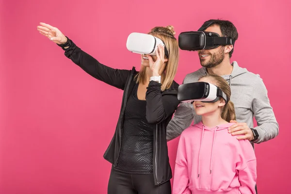 Familie nutzt Virtual-Reality-Headsets zusammen, isoliert auf rosa — Stockfoto