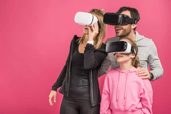 Возбужденная семья, использующая VR-наушники, изолированные на розовом — стоковое фото