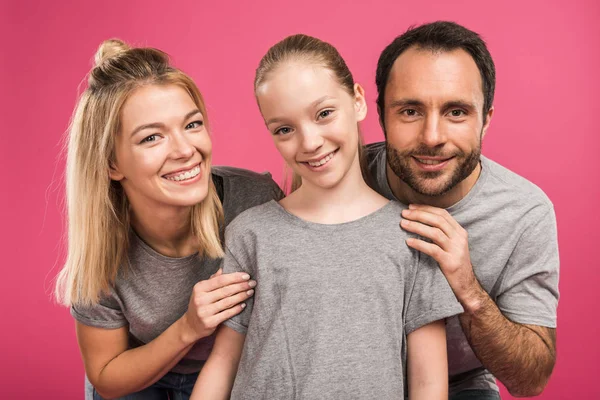 Pais sorridentes abraçando filha pré-adolescente, isolado em rosa — Fotografia de Stock