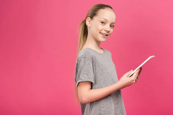 Entzückendes blondes Kind mit digitalem Tablet, isoliert auf rosa — Stockfoto