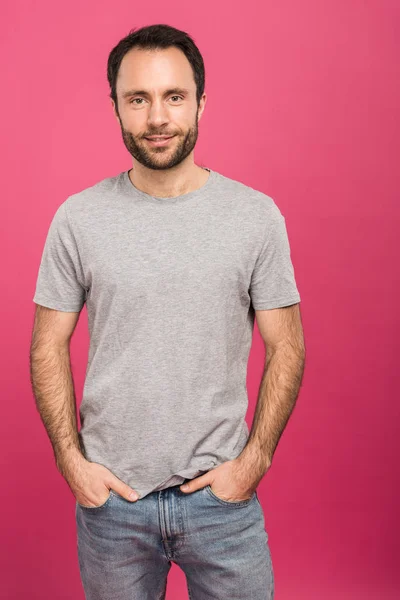 Homem bonito posando com as mãos nos bolsos, isolado em rosa — Fotografia de Stock