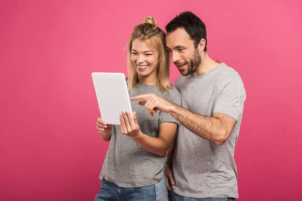 Feliz casal bonito usando tablet digital, isolado em rosa — Fotografia de Stock
