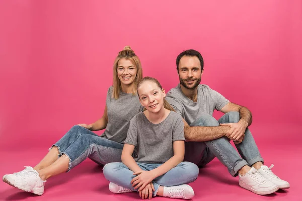 Hermosa familia con hija feliz sentado en rosa - foto de stock