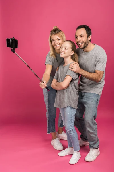 Beautiful family taking selfie on smartphone, on pink — Stock Photo