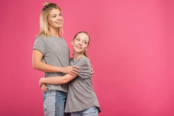 Adorável filha abraçando bela mãe isolada em rosa — Fotografia de Stock