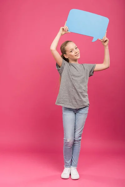 Smiling preteen kid holding blue speech bubble, isolated on pink — Stock Photo