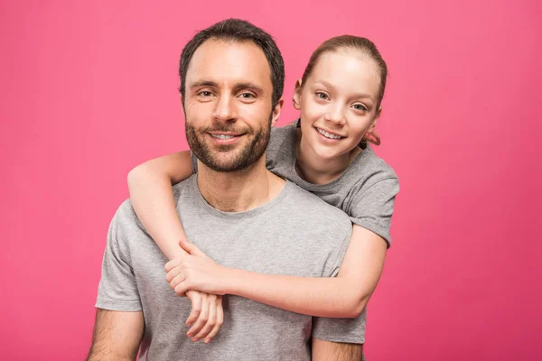 Lächelnde blonde Tochter umarmt ihren Vater, isoliert auf rosa — Stockfoto