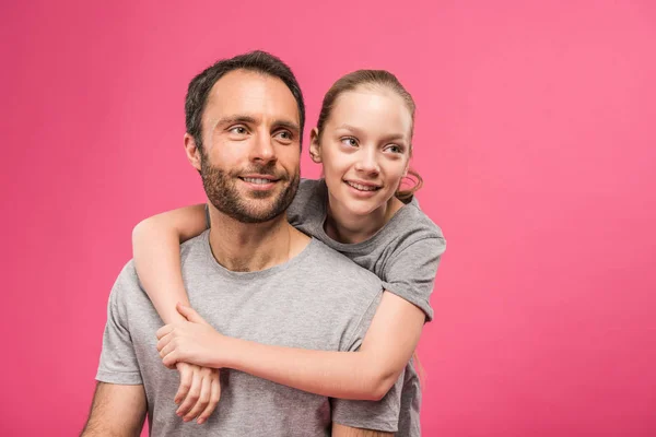 Hija rubia sonriente abrazando a su padre, aislada en rosa - foto de stock