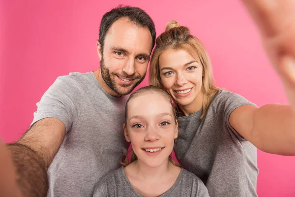 Улыбающаяся семья делает селфи вместе, изолированные на розовый — стоковое фото