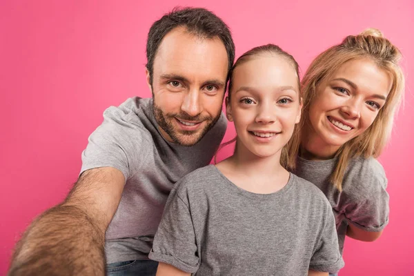 Lächelnde Eltern und Tochter beim gemeinsamen Selfie, isoliert auf rosa — Stockfoto
