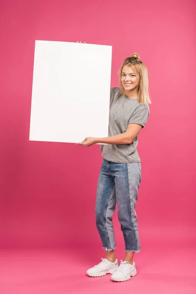 Smiling woman posing with empty board, isolated on pink — Stock Photo