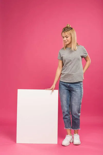 Attraente donna in posa con bordo vuoto con spazio copia, isolato su rosa — Foto stock