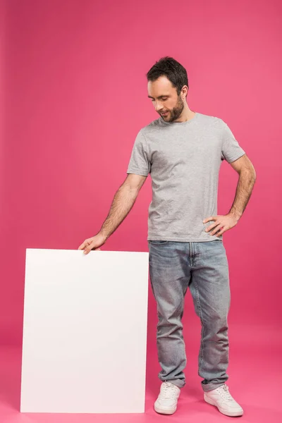 Schöner Mann, der neben leerem Brett steht, isoliert auf rosa — Stockfoto