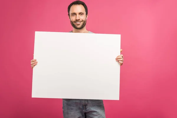 Fröhlicher Mann posiert mit leerem Brett, isoliert auf rosa — Stockfoto