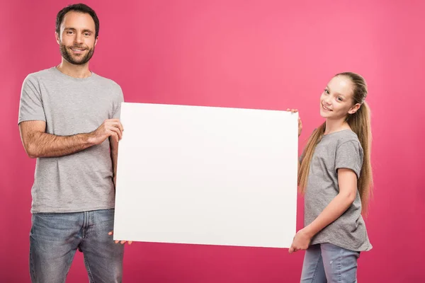 Father and adorable daughter posing with empty board, isolated on pink — Stock Photo