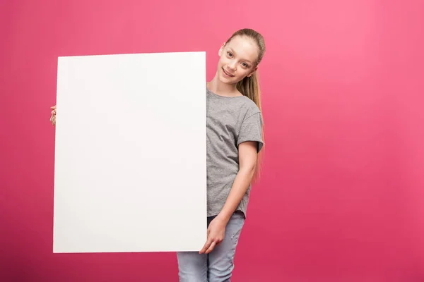 Niño adorable posando con tablero vacío, aislado en rosa - foto de stock