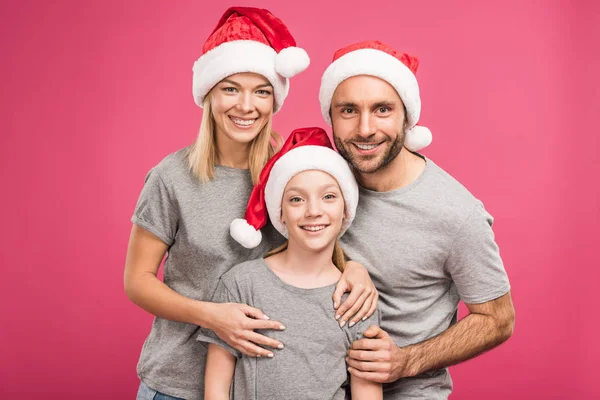 Porträt einer glücklichen Familie mit Weihnachtsmützen, isoliert auf rosa — Stockfoto