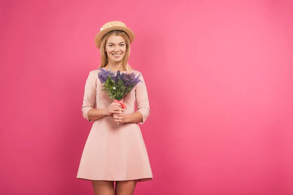 Heureux attrayant femme en robe posant avec des fleurs, isolé sur rose — Photo de stock