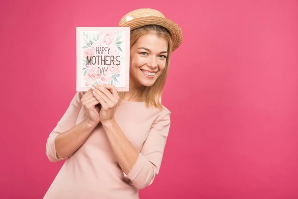 Biglietto di auguri per una donna sorridente che regge la giornata delle madri felici, isolata sul rosa — Foto stock