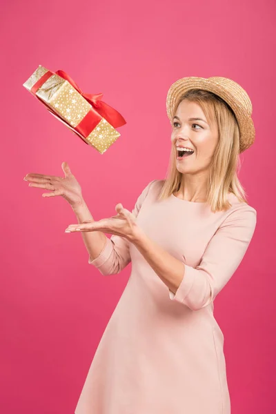 Aufgeregte blonde Frau wirft Geschenkbox isoliert auf rosa — Stockfoto