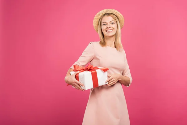 Fröhliche Frau hält Geschenkbox isoliert auf rosa — Stockfoto