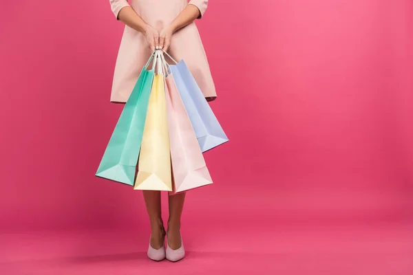 Vista parcial de chica con bolsas de compras, aislado en rosa - foto de stock