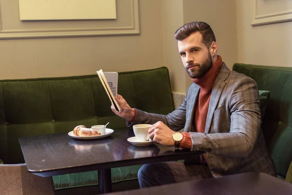 Homme élégant en tenue formelle assis à table pendant le déjeuner et la lecture de journal dans le restaurant — Photo de stock