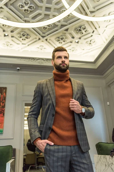 Serious handsome man in formal wear posing with hand in pocket in restaurant — Stock Photo