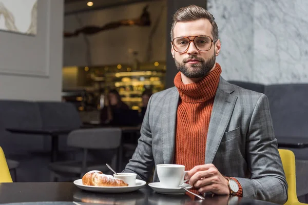 Hombre guapo en ropa formal y gafas mirando a la cámara durante el almuerzo en el restaurante - foto de stock