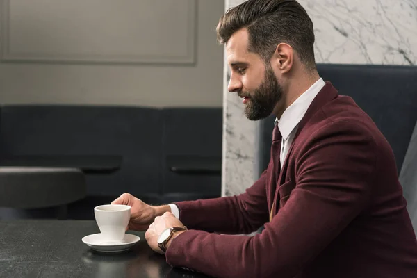 Schöner Geschäftsmann in formeller Kleidung, der mit einer Tasse Kaffee im Restaurant am Tisch sitzt — Stockfoto