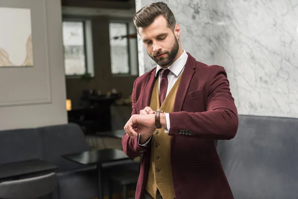 Hombre de negocios serio en ropa formal mirando el reloj - foto de stock