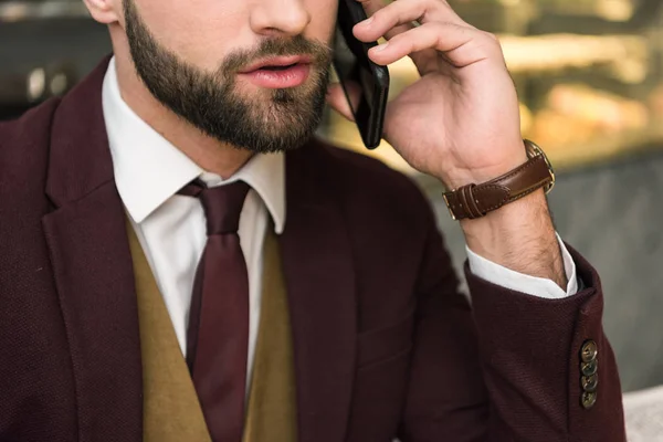Recortado vista de hombre de negocios en ropa formal hablando en el teléfono inteligente - foto de stock