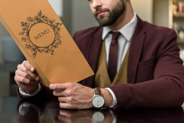 Обрізаний вид бізнесмена в офіційному одязі, сидячи в ресторані і тримаючи меню — стокове фото