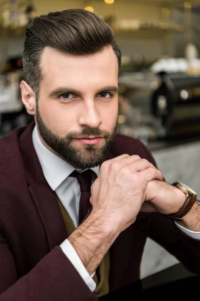 Portrait of handsome businessman in formal wear with folded hands looking at camera — Stock Photo