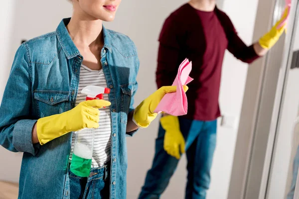 Vista ritagliata di ragazza in guanti di gomma che tiene attrezzature per la pulizia a casa — Foto stock