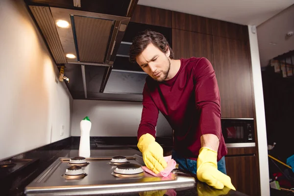 Bel homme en gants de caoutchouc nettoyage cuisine à la maison — Photo de stock