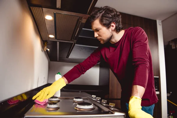 Hombre serio en guantes de goma limpieza cocina - foto de stock