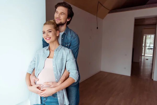 Sonriente hombre mantener las manos en el vientre de la esposa embarazada - foto de stock