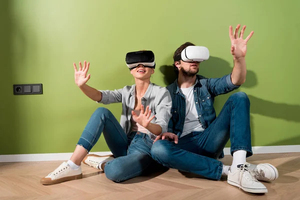 Girl and man with virtual reality headsets on heads sitting on floor and playing video game — Stock Photo