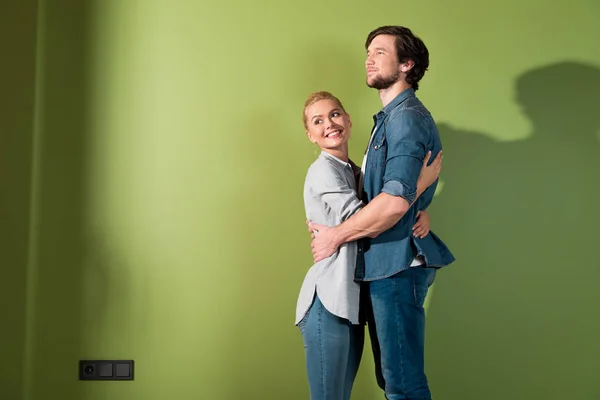 Sorridente coppia di famiglia abbracciati da muro verde — Foto stock