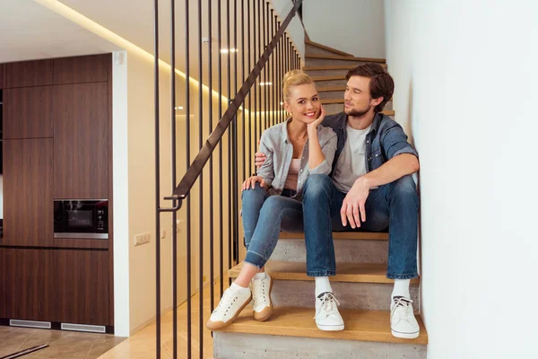 Bel homme assis sur les escaliers et regardant belle femme — Photo de stock