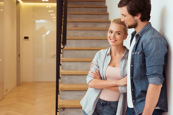 Attractive girl and handsome man standing near stairs at home — Stock Photo