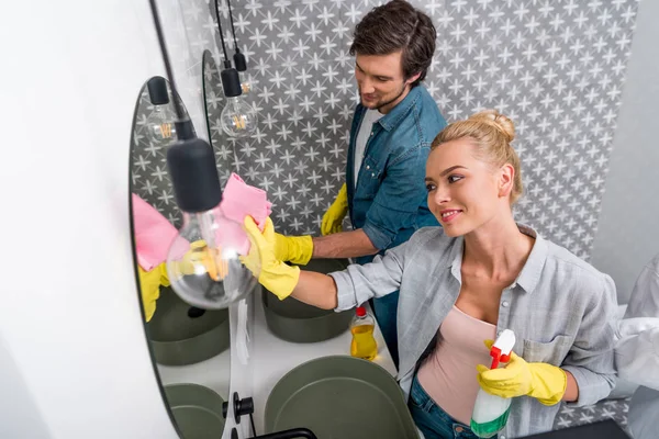 Hombre guapo y hermosa chica limpiando espejos en el baño - foto de stock