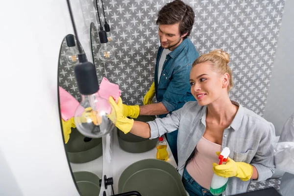 Bel homme et belle fille nettoyage miroirs dans la salle de bain — Photo de stock