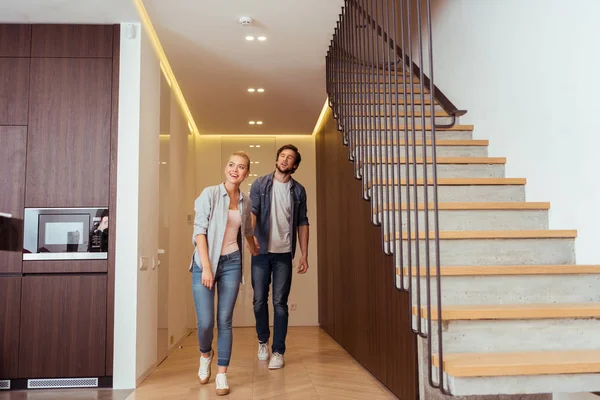 Sorridente coppia di famiglia che si tiene per mano vicino alle scale a casa — Foto stock