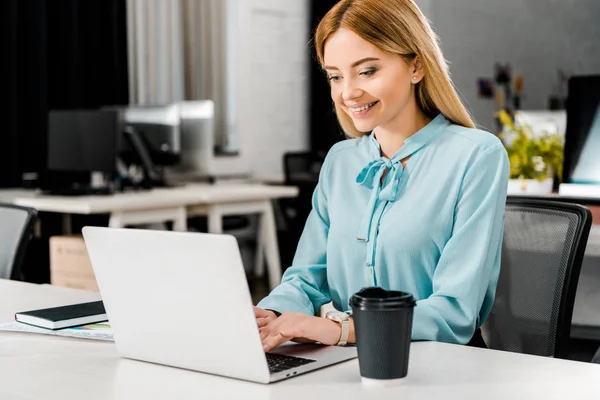 Портрет улыбающейся деловой женщины, работающей на ноутбуке в офисе — стоковое фото