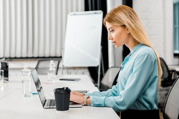 Seitenansicht einer fokussierten Geschäftsfrau, die im Büro am Laptop arbeitet — Stockfoto