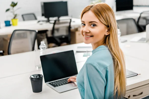 Mulher de negócios sorridente no local de trabalho com laptop e café para ir no escritório — Fotografia de Stock