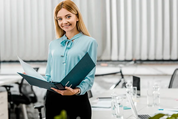 Retrato de mujer de negocios sonriente con carpeta en la oficina - foto de stock