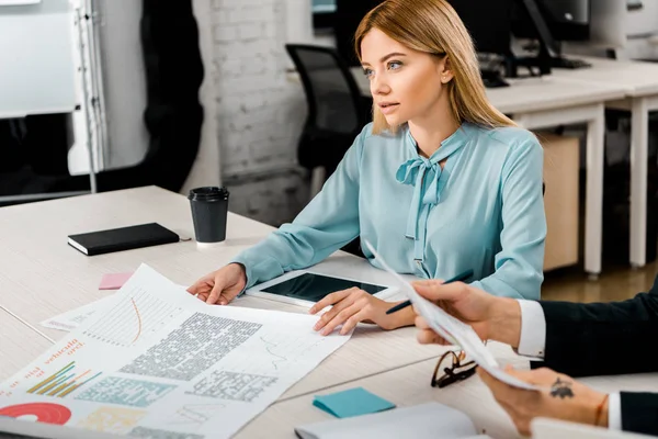 Cropped shot of businesswoman and colleague at workplace with documents and tablet — Stock Photo